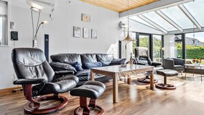 Una sala moderna con mobiliario de cuero, techo de cristal y obras de arte en las paredes.