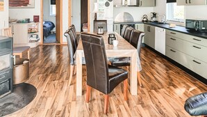 Una cocina moderna con comedor, suelo de madera y vistas al exterior.