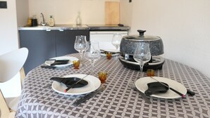 A dining table set with plates, cutlery, and wine glasses in a modern kitchen with a microwave and cabinets. - 2-room apartment calm near slopes, 6 people (Saint-Gervais-les-Bains)