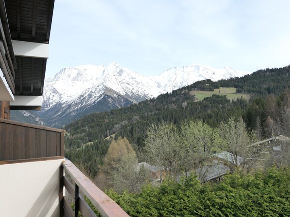 A mountain view from a balcony with snow-capped peaks in the background.