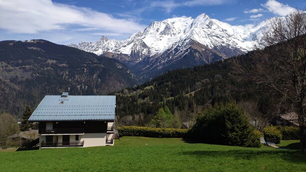 A two-story building with a blue roof, surrounded by a green lawn and trees, with snow-capped mountains in the background. - 2-room apartment calm near slopes, 6 people (Saint-Gervais-les-Bains)