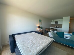 A compact room with a bed, a sofa, a small desk, and a kitchenette. - Modern Studio in Biarritz with Parking and Ocean View (Biarritz)