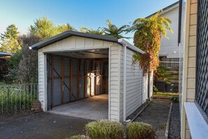 A garage with a metal door, wooden interior, and a concrete floor. - Cooper's Lakeside - Lakefront, Kayaks, Sleeps 5 (Rotorua)