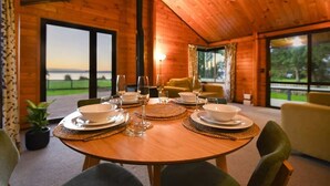 Comedor de madera con una mesa dispuesta para cuatro, ventanas amplias y vista al exterior.