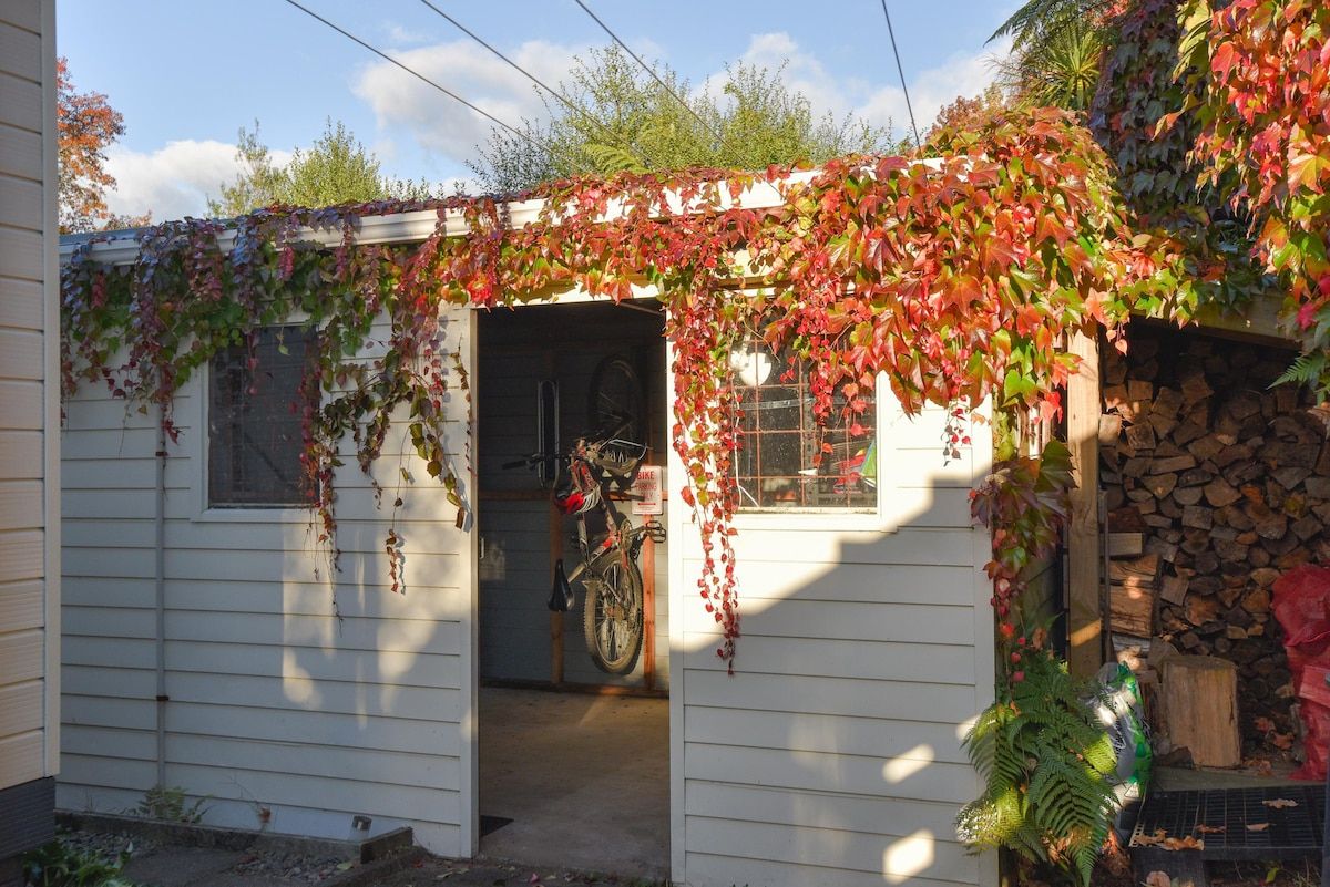 Un petit bâtiment d’un seul étage, doté d’une entrée abritée, où est garé un vélo, et où l’on peut voir une pile de bois de chauffage sur la droite.