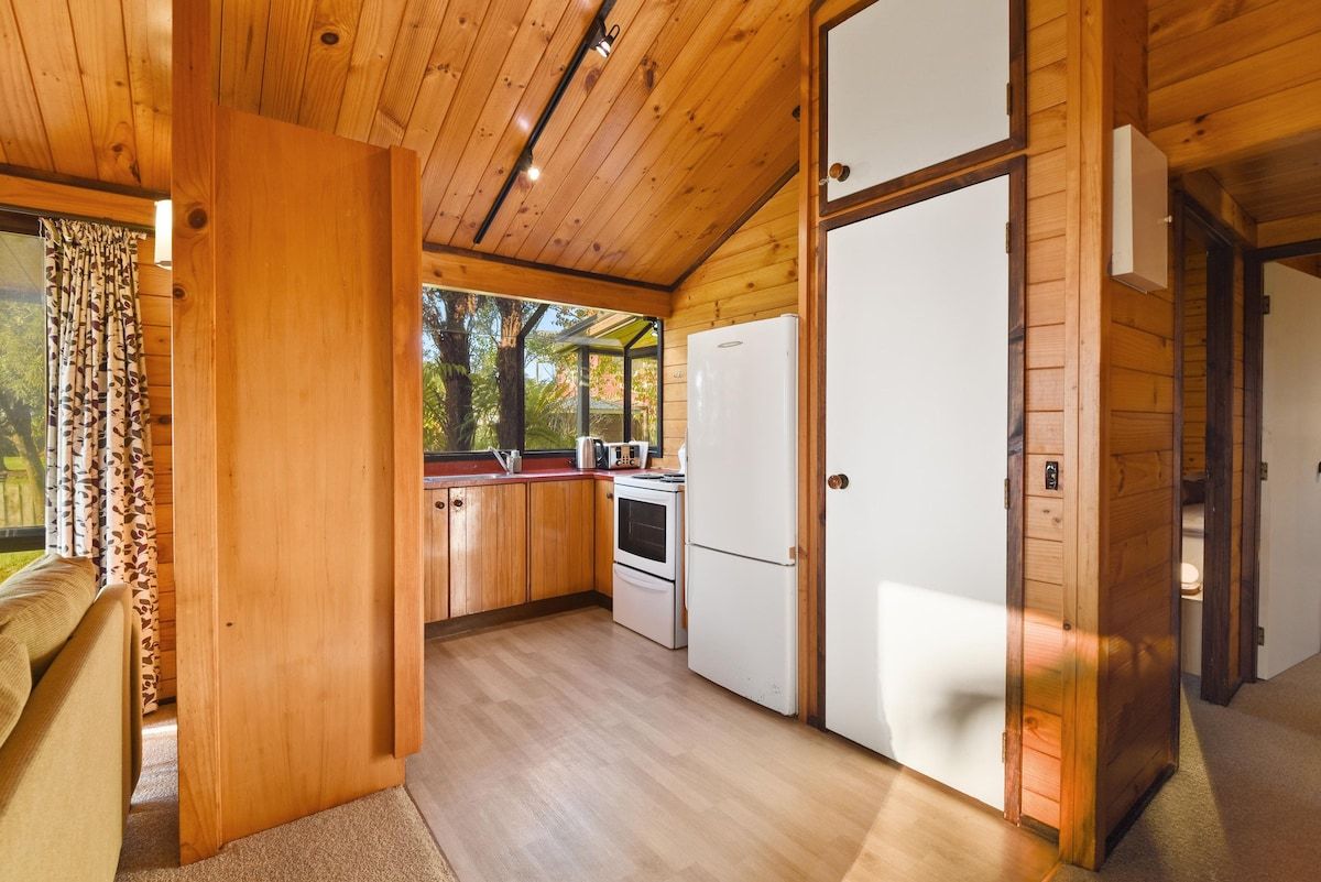 Una cocina compacta con armarios de madera, un refrigerador y una estufa.