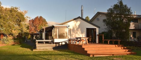 A residential property with a covered patio area, a wooden deck, and a small building with a chimney.