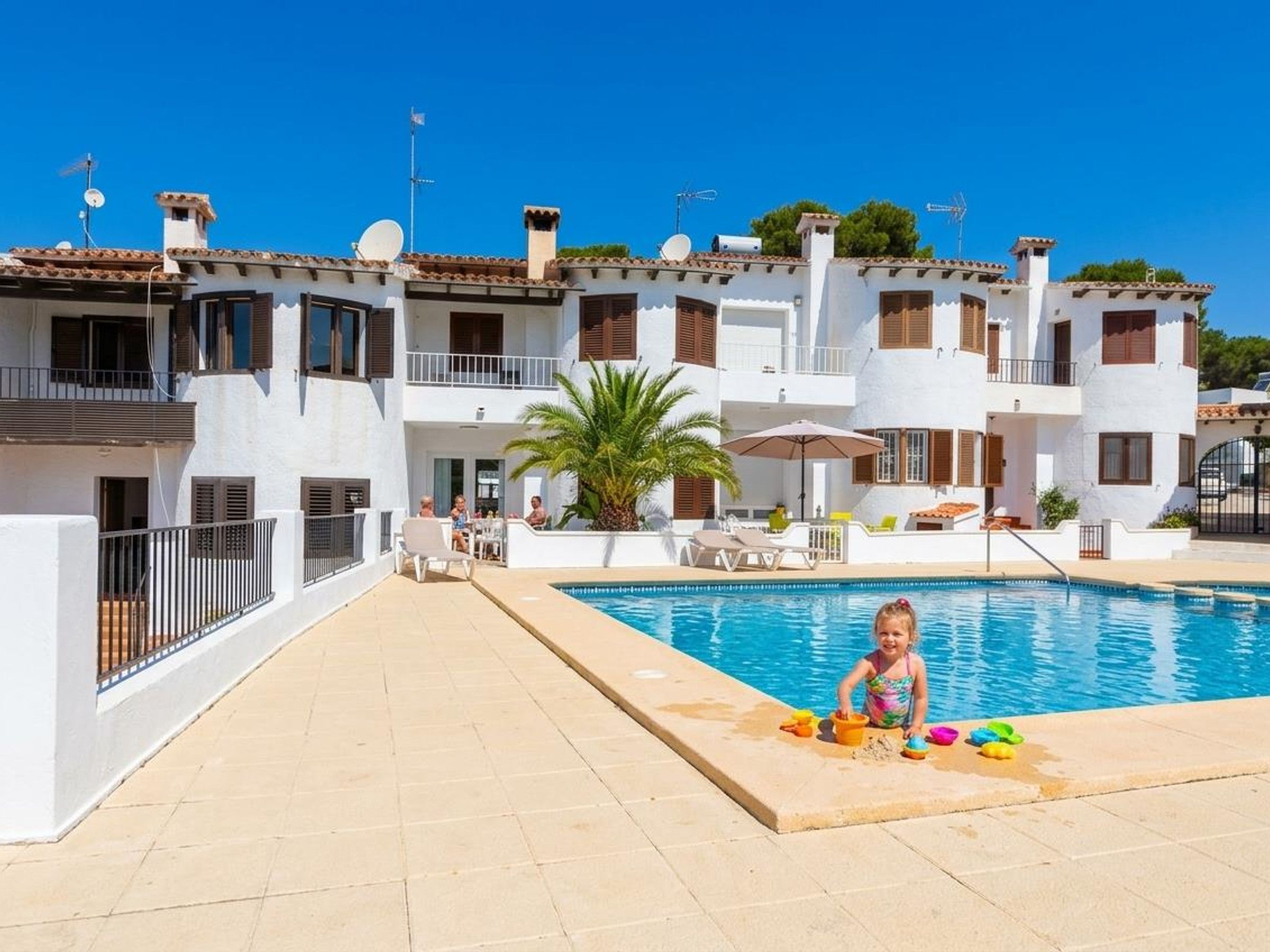 A residential building with a swimming pool, balconies, and outdoor seating areas.