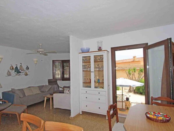 A living room with a sofa, chairs, a dining table, and a cabinet.