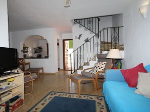 A living room with a TV, bookshelves, a sofa, and a staircase.
