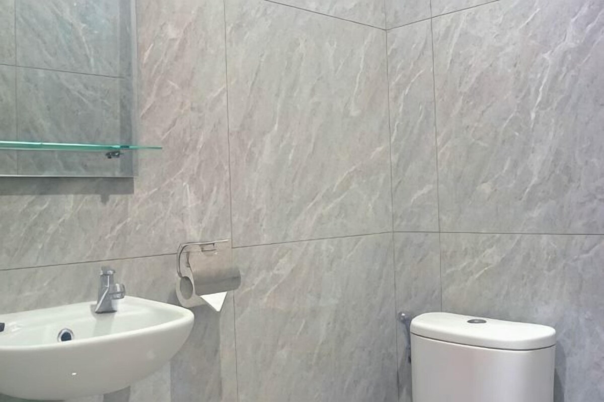 A bathroom with a sink, toilet, and marble walls.