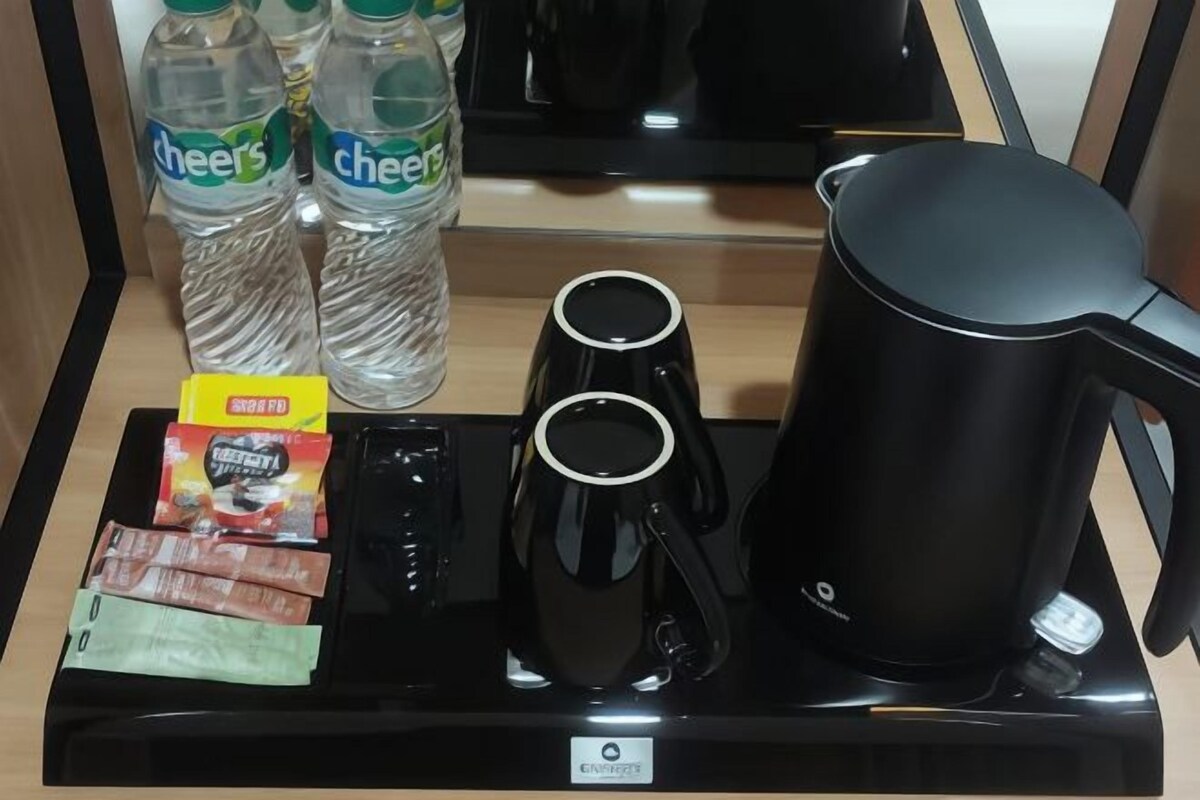A tray with bottled water, coffee cups, a kettle, and packaged snacks.