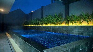 Una piscina interior amb sòl de rajola i una paret baixa amb plantes.