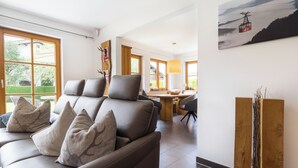 Una sala de estar moderna con sofá, comedor y un ventanal grande.