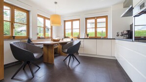 Una cocina moderna con una mesa de comedor de madera, dos sillas y ventanas amplias.