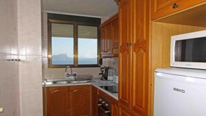 A kitchen with wooden cabinets, a sink, a microwave, and a window with a view.