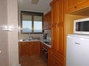 A kitchen with wooden cabinets, a sink, a microwave, and a window with a view.