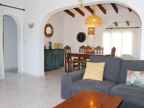 A living room with a sofa, a wooden coffee table, and a dining area with a table and chairs. - Charming Villa in Moraira with Private Pool, Near Beach and Amenities, Pet-Friendly (Moravit)