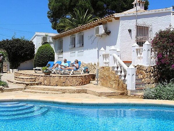A poolside area with a stone staircase leading to a white building with a balcony.