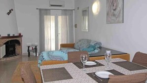 A room with a bed, a dining table set for two, a fireplace, and a painting on the wall. - Cozy Holiday Home in Moraira with Communal Pool, Near Golf & Beach, Perfect for Families (Moraira)