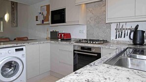 A compact kitchen with a washing machine, microwave, stove, oven, and a sink. - Cozy Holiday Home in Moraira with Communal Pool, Near Golf & Beach, Perfect for Families (Moraira)