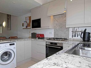 A compact kitchen with a washing machine, microwave, stove, oven, and a sink.