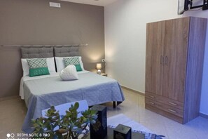 A bedroom with a bed, a nightstand, a wardrobe, and a potted plant. - SUMMER DREAM - Double or twin room (Mazara del Vallo)