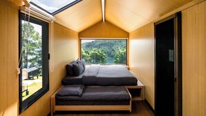 Une chambre à coucher de taille réduite, dotée d’une lucarne, d’un lit et d’un banc.
