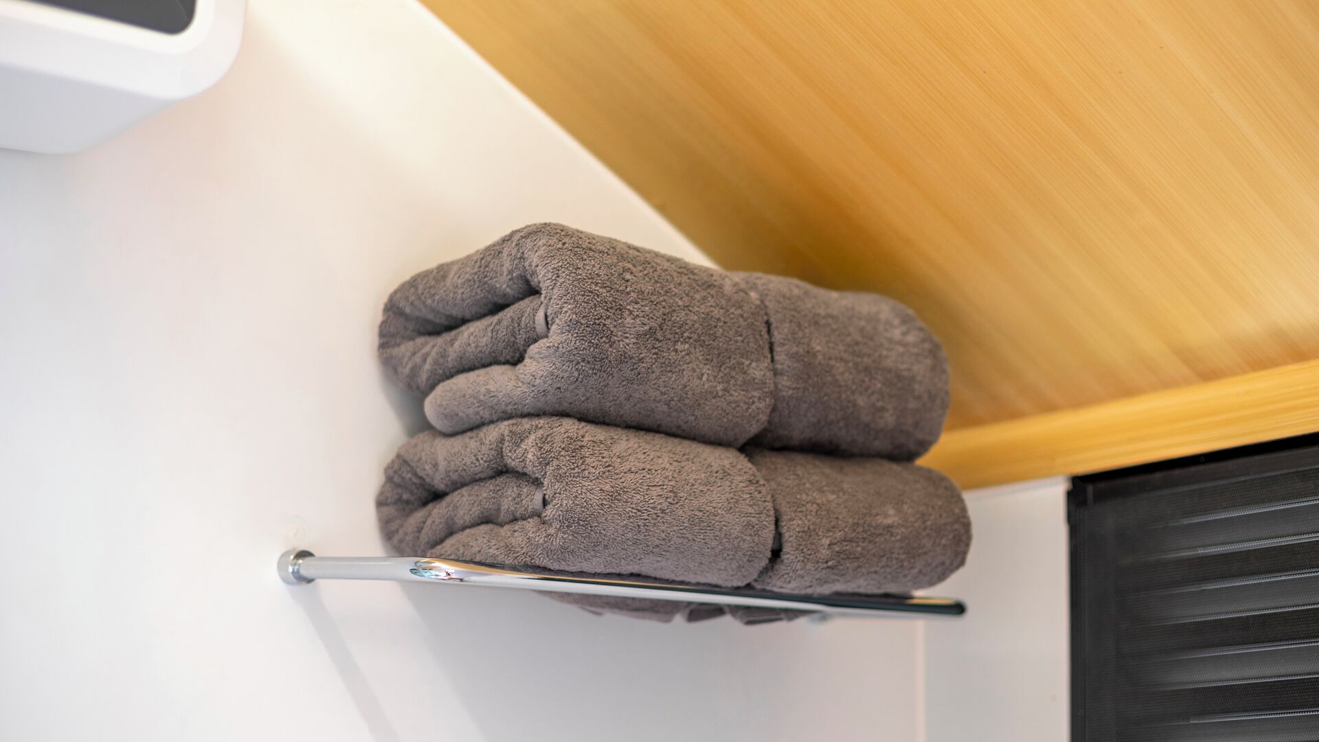 A neatly folded gray towel on a metal towel rack in a bathroom.