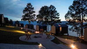 Un complexe hôtelier au bord d’un lac, avec des chalets, des espaces de détente en plein air et un foyer.
