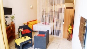 Une pièce comprenant un lit, deux canapés, une petite table et un téléviseur fixé au mur.