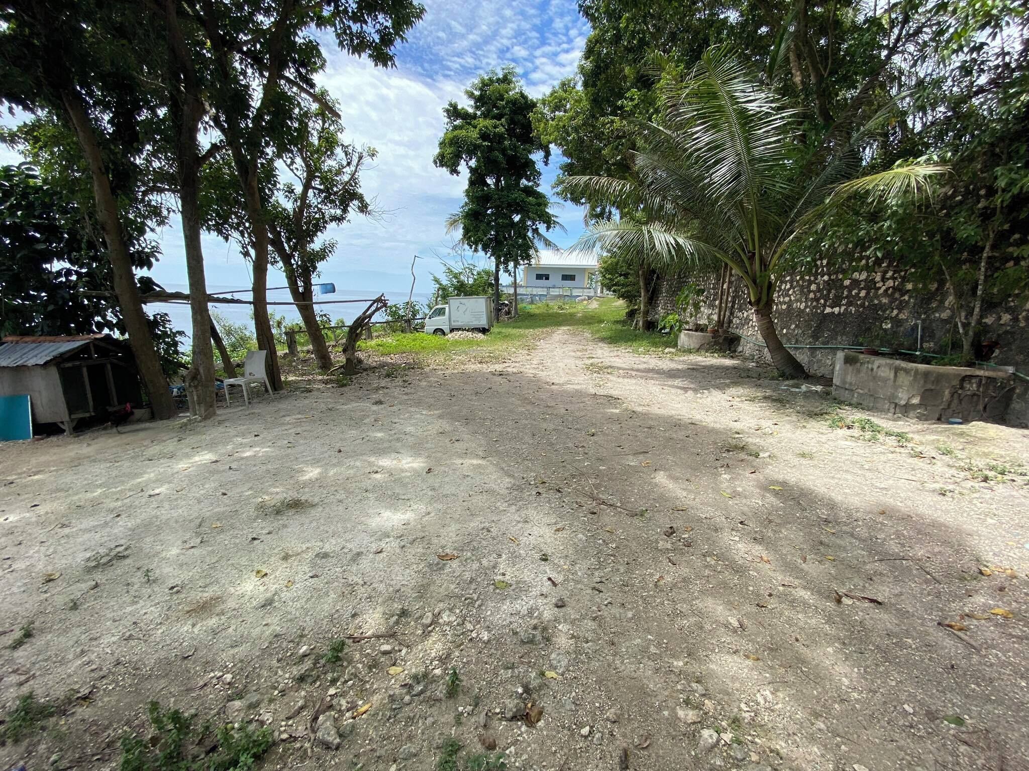 A dirt path leading to a building with a view of the sea.