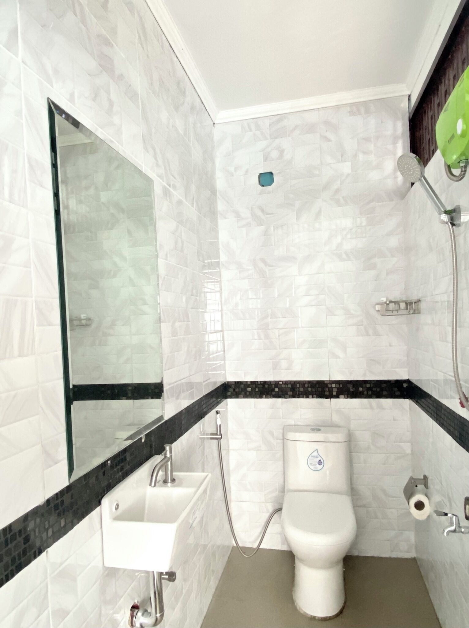 Casa de banho com azulejos de mármore branco, moldura preta e branca, cabine de duche com vidro, sanita branca e lavatório com torneira.