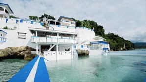 A waterfront hotel with a blue and white color scheme, featuring a prominent staircase leading to an upper level.