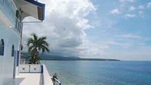 A coastal building with a clear view of the sea and a distant island.