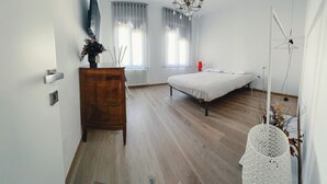 A bedroom with a bed, a dresser, a chandelier, and a radiator.