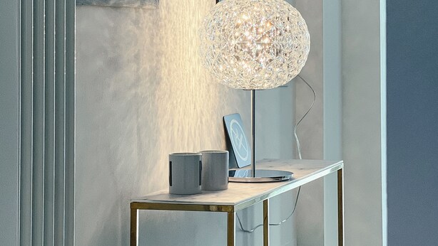 A modern desk with a decorative lamp, a framed picture, and a small speaker.