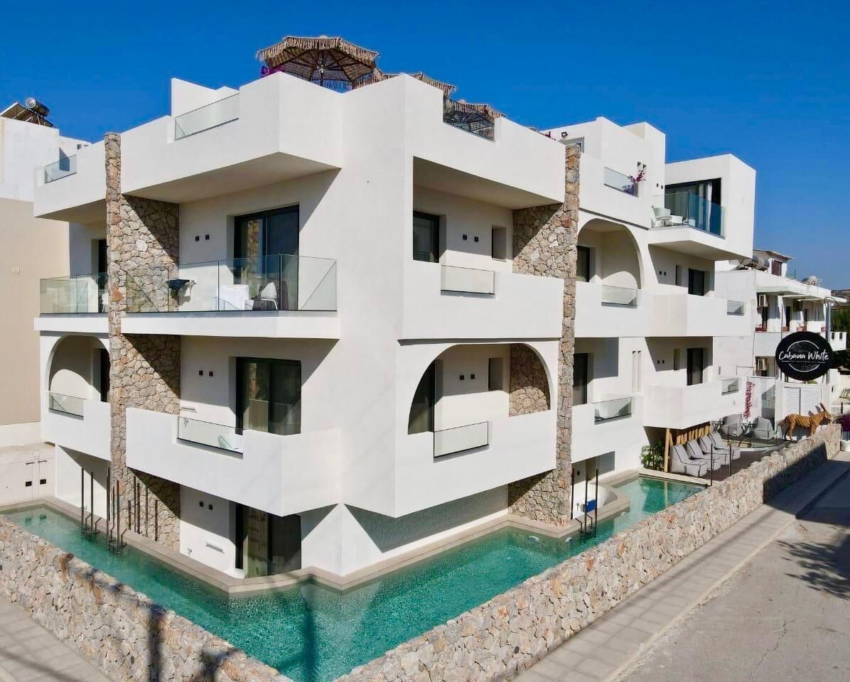 A modern multi-story hotel with balconies, a swimming pool, and a sign indicating 'Cabanas White'.