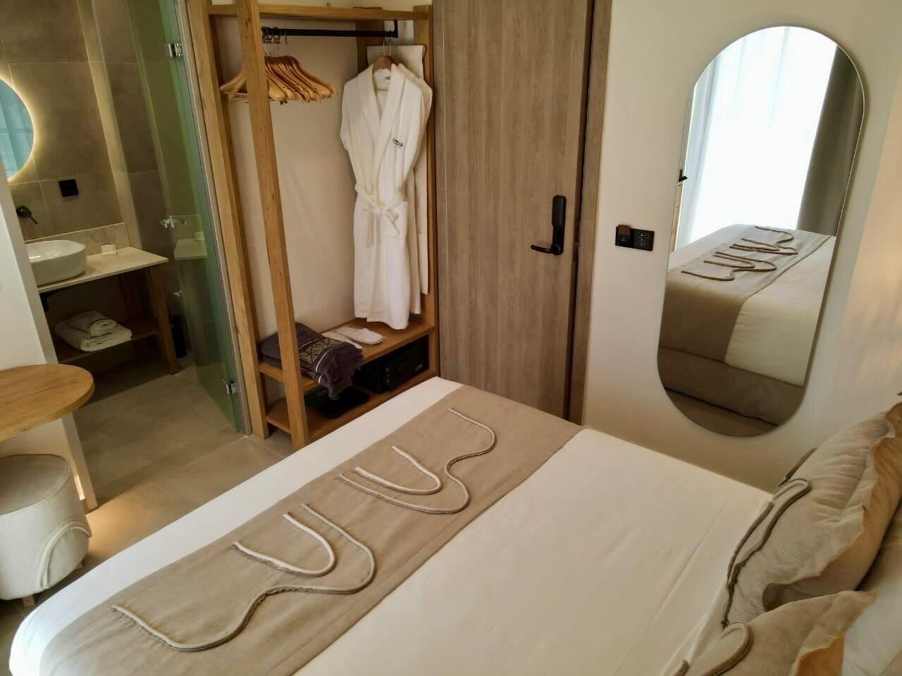 Ein Schlafzimmer mit Bett, Spiegel, Kleiderschrank und Bad.