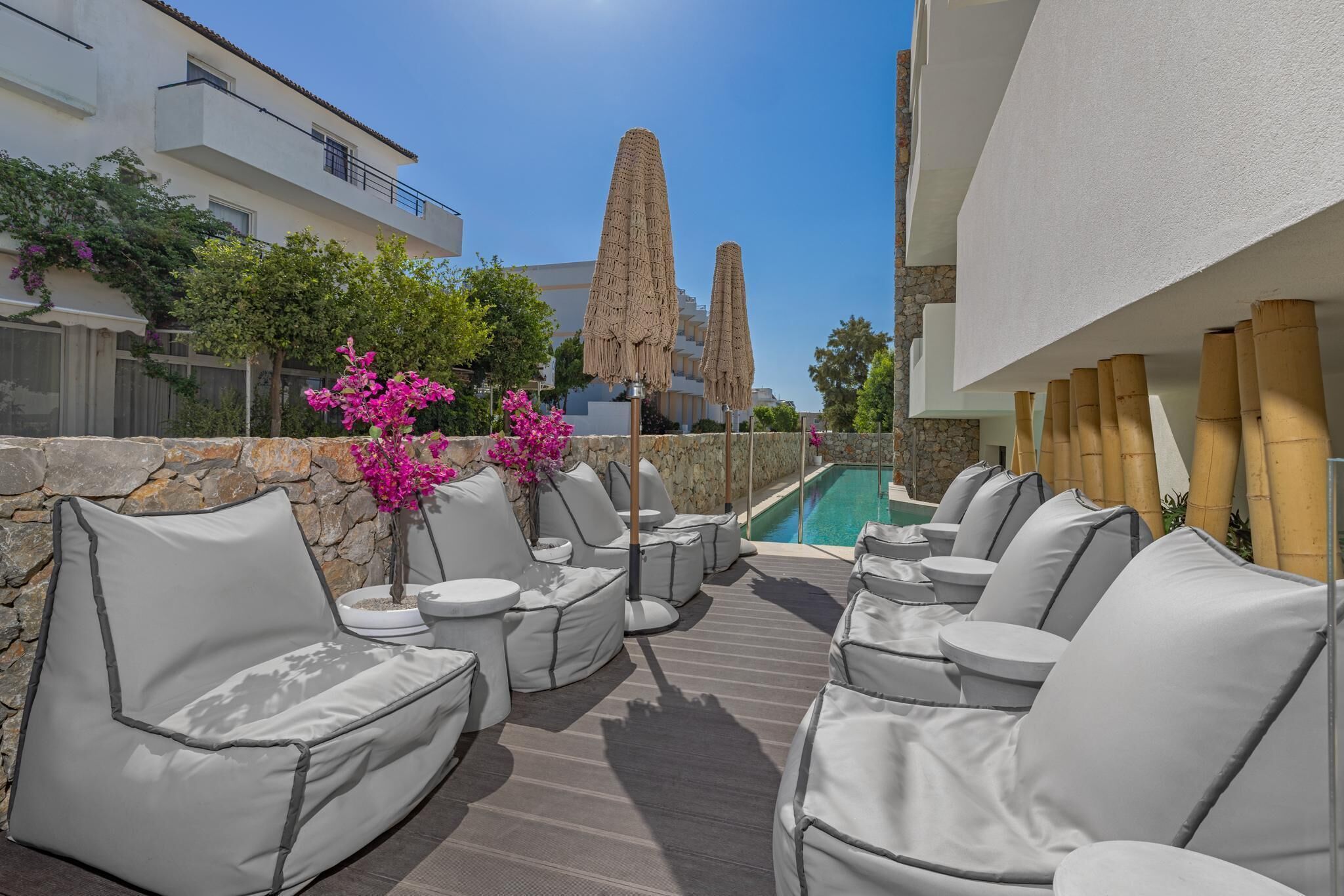 Una terraza en la azotea con mobiliario exterior, una piscina y vistas a un edificio alto.