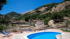 A pool area with lounge chairs and a view of a mountainous landscape. - Masseria rocca di Gonato (Castelbuono)