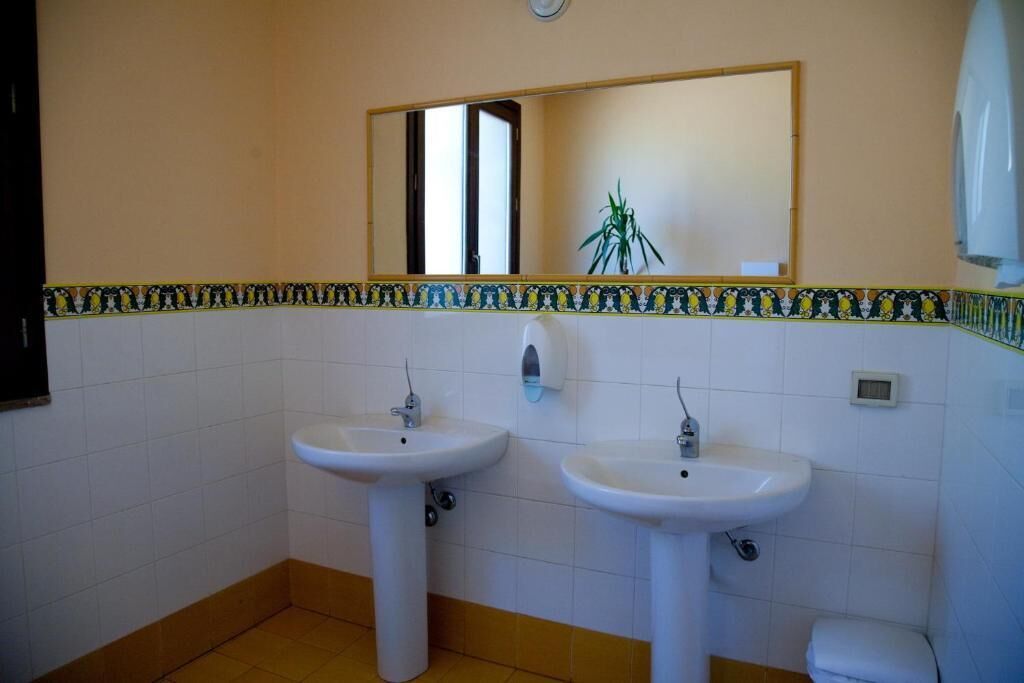 Un baño con dos lavamanos, un espejo y un inodoro.