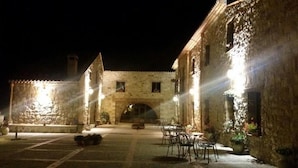 A courtyard with stone buildings, a central archway, and outdoor seating. - Masseria rocca di Gonato (Castelbuono)