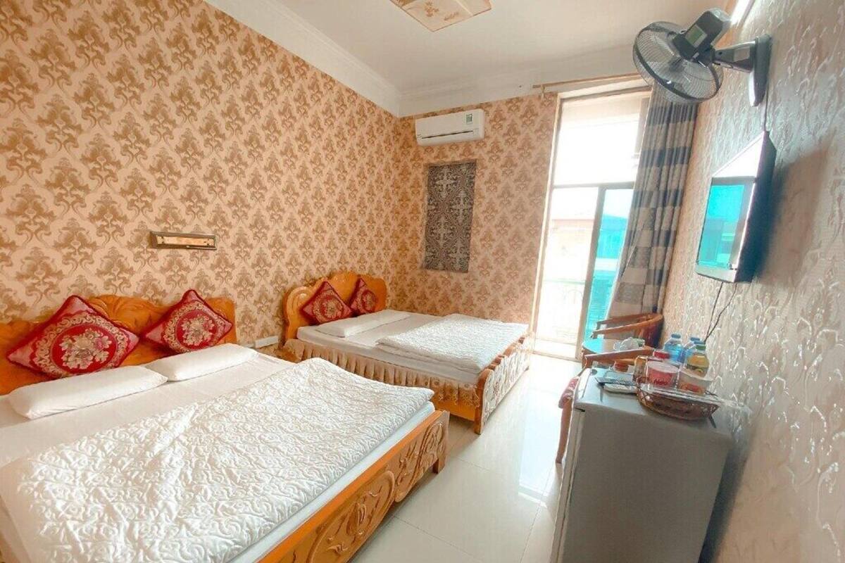 Ein Hotelzimmer mit zwei Betten, einem kleinen Schreibtisch, einer Klimaanlage und einem fenster mit Vorhängen.