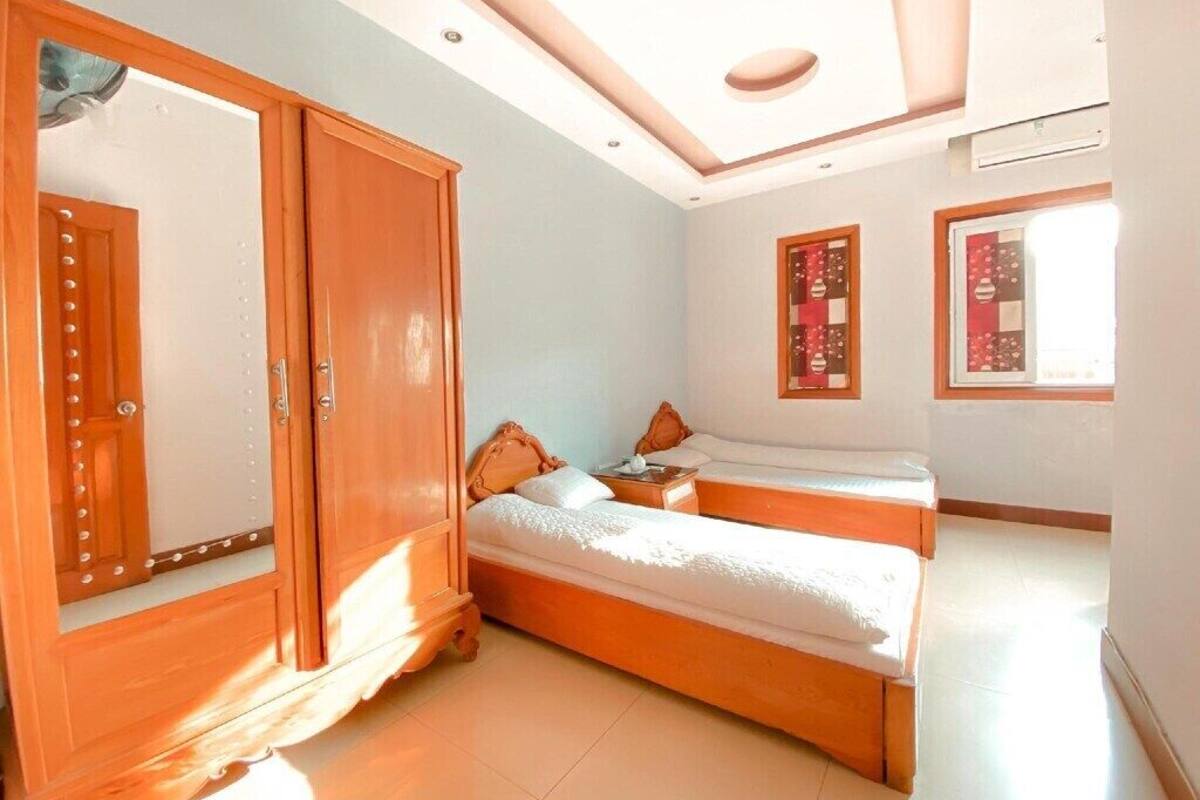 Ein Zimmer mit zwei Betten, einem Kleiderschrank und einer Decke mit Einbuchtungslampen.