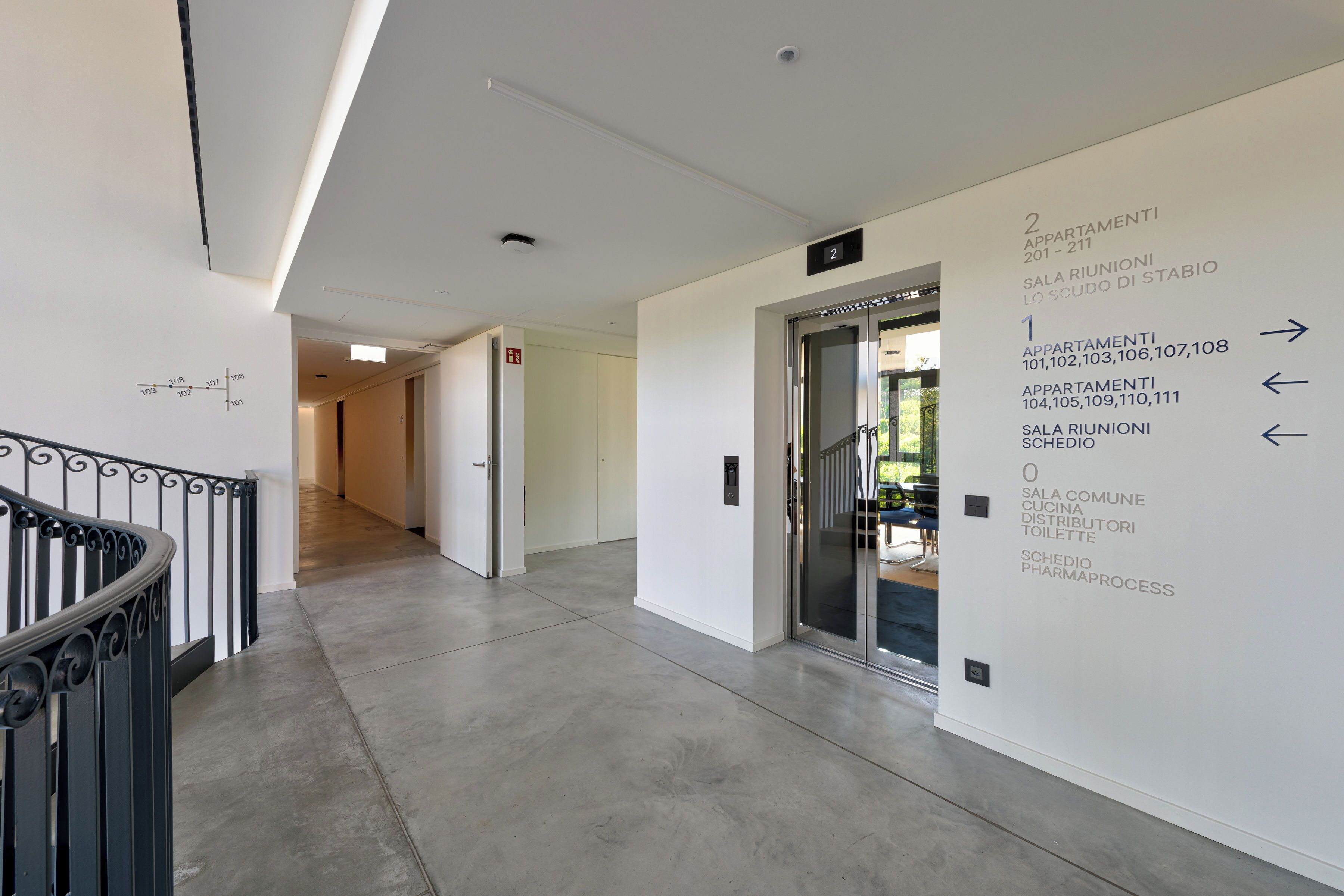 A modern hallway with directional signs to various apartments and facilities.