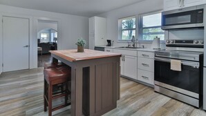 Cozinha moderna com ilha central, eletrodomésticos de aço inoxidável e vista para a sala de estar.