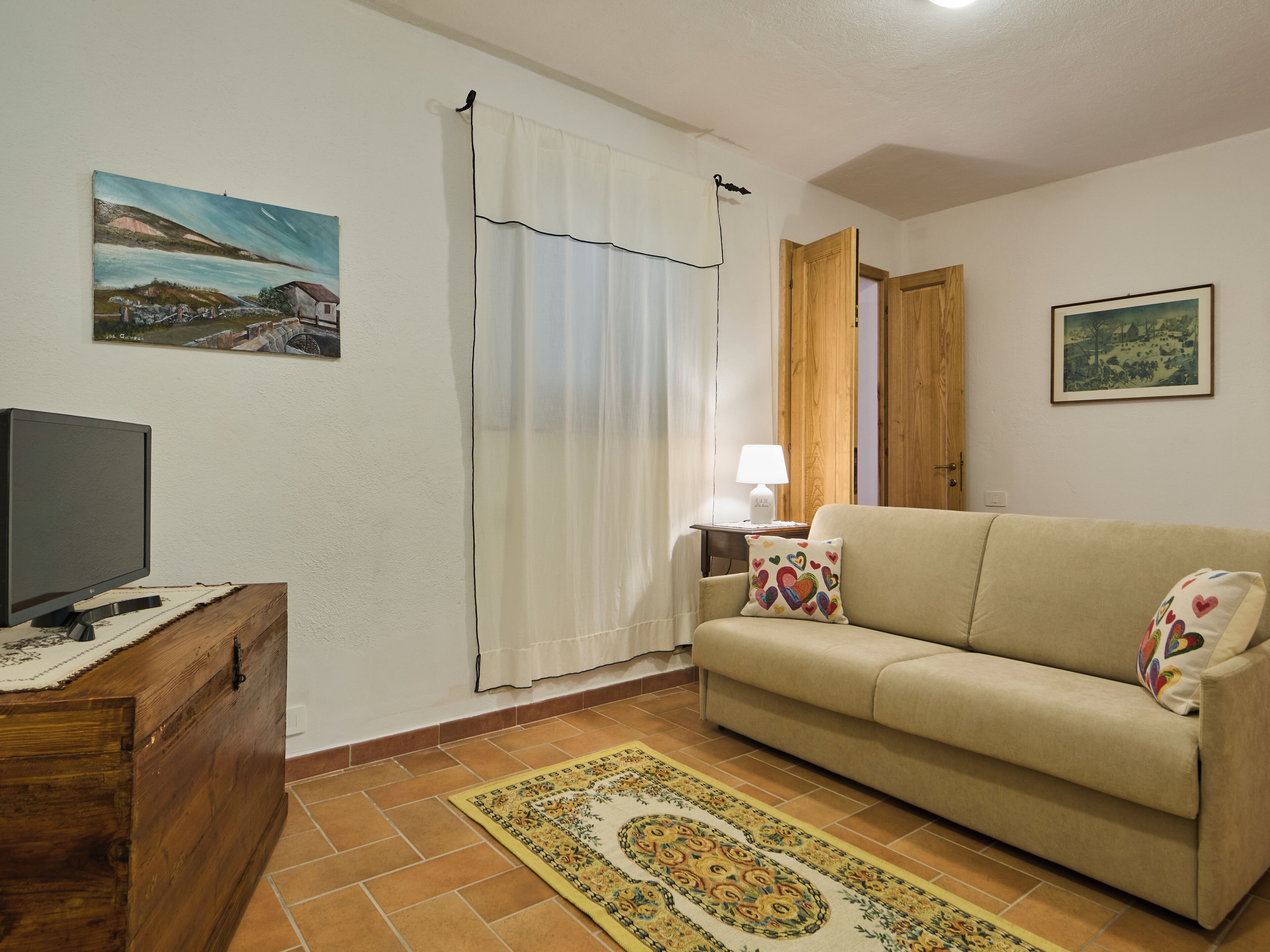 Una sala de estar con un sofá, una televisión, una lámpara y una alfombra.