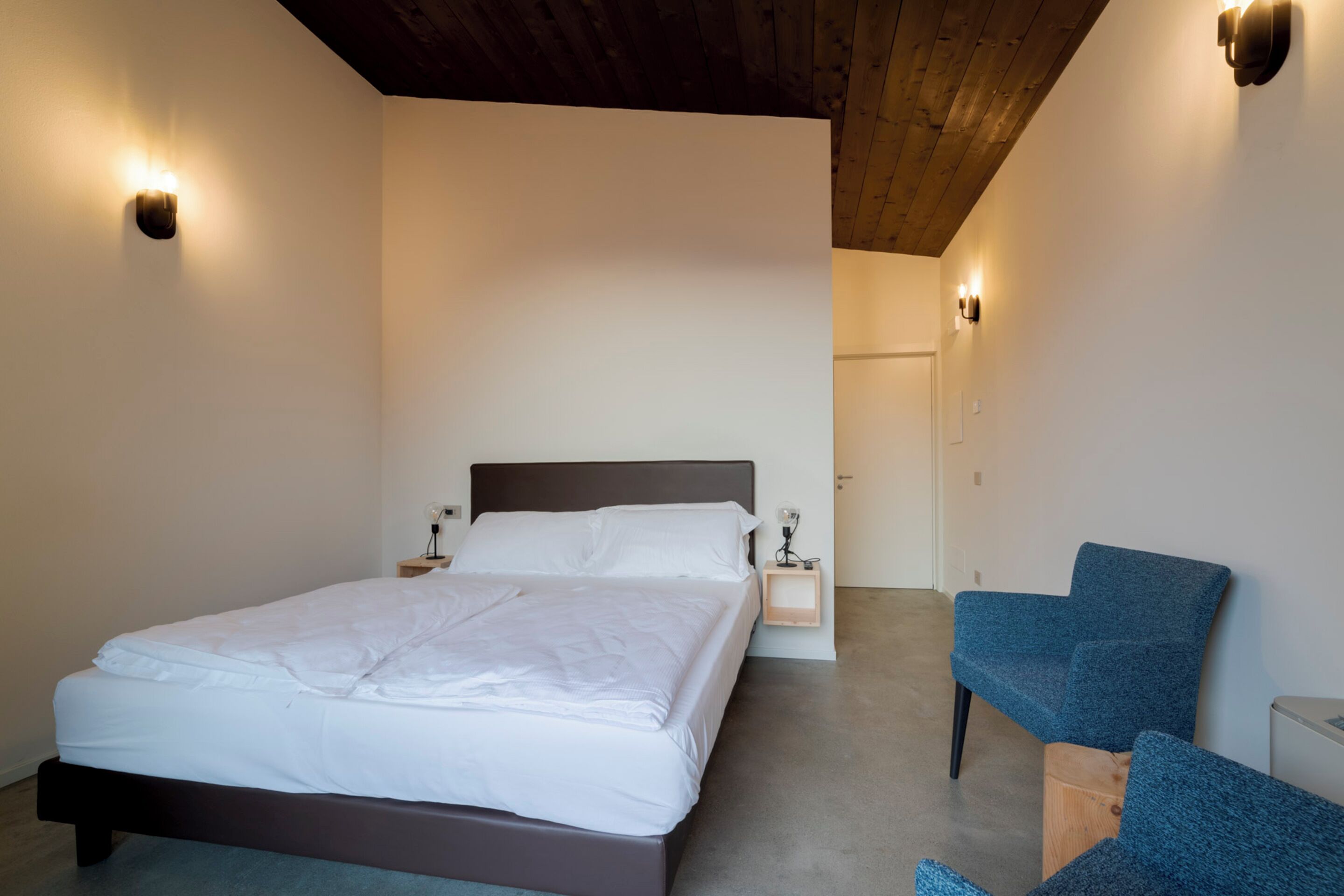 A bedroom with a bed, bedside tables, and a blue chair.