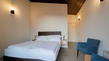 A bedroom with a bed, bedside tables, and a blue chair.